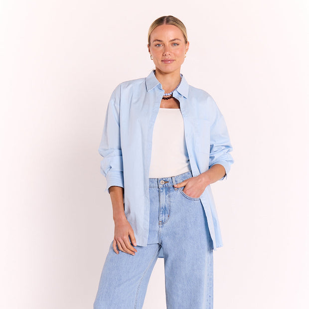 Powder blue cotton button-down shirt with chest pocket and curved hem