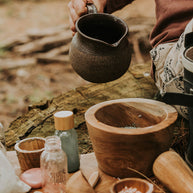 Child sitting outdoors mixing potions from the Wild Adventure kit on a tree trunk