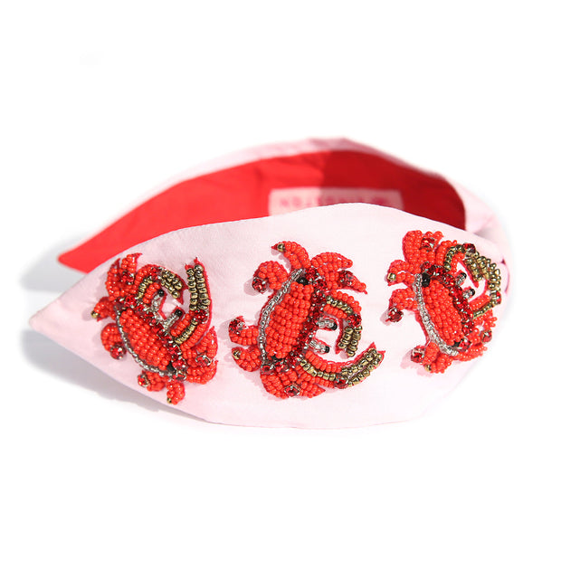Hand-beaded statement headband with crab design on pink background