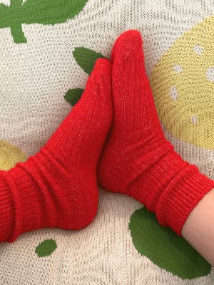 Bed and Butter cosy red ankle socks styled against white waffle and boucle cushions