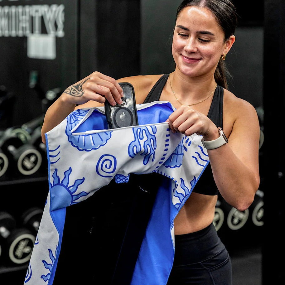 Blue and white fish and shell print towel hooked over gym bench
