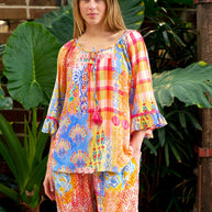 Model wearing the Alizee Top in a colourful multi patch print with 3/4 ruffled sleeves and tie neckline.