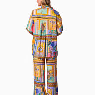 Model wearing the Kaena Pants in Multi Print featuring a straight leg, elastic waist, drawstring and bold patch-style print