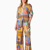 Model wearing the Kaena Pants in Multi Print featuring a straight leg, elastic waist, drawstring and bold patch-style print