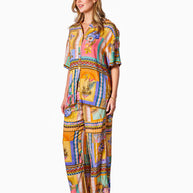 Model wearing the Kaena Pants in Multi Print featuring a straight leg, elastic waist, drawstring and bold patch-style print