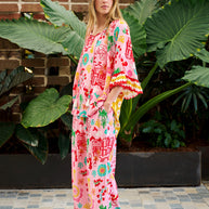 Model wearing the Mercedes Top in Pink Yellow featuring a tie neckline, 3/4 bell sleeves and a bold multicolour print.