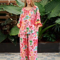 Model wearing the Mercedes Top in Pink Yellow featuring a tie neckline, 3/4 bell sleeves and a bold multicolour print.