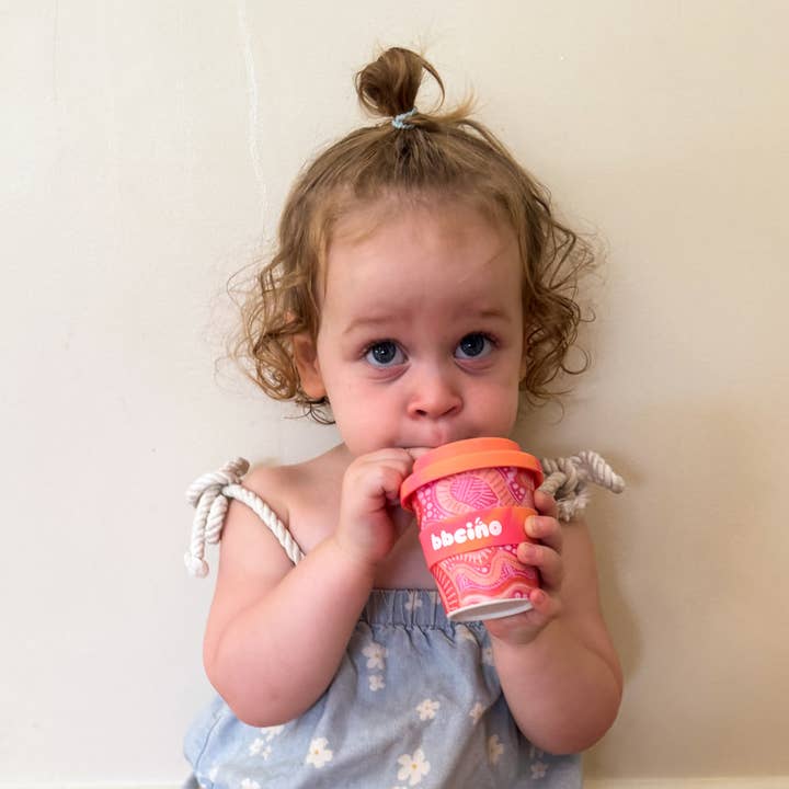 Eco-friendly bamboo kids cup featuring Merindah-Gunya Indigenous artwork in warm pink and orange tones