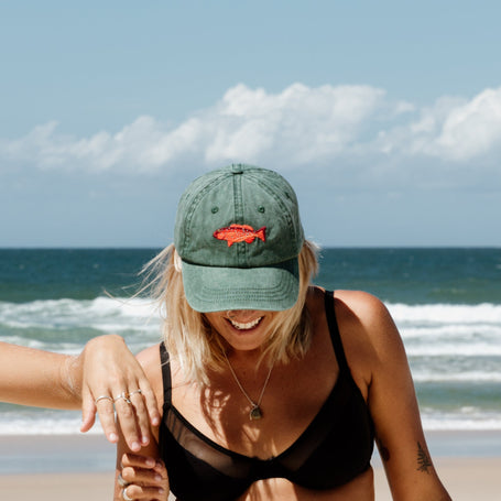 Faded green baseball cap with embroidered coral trout