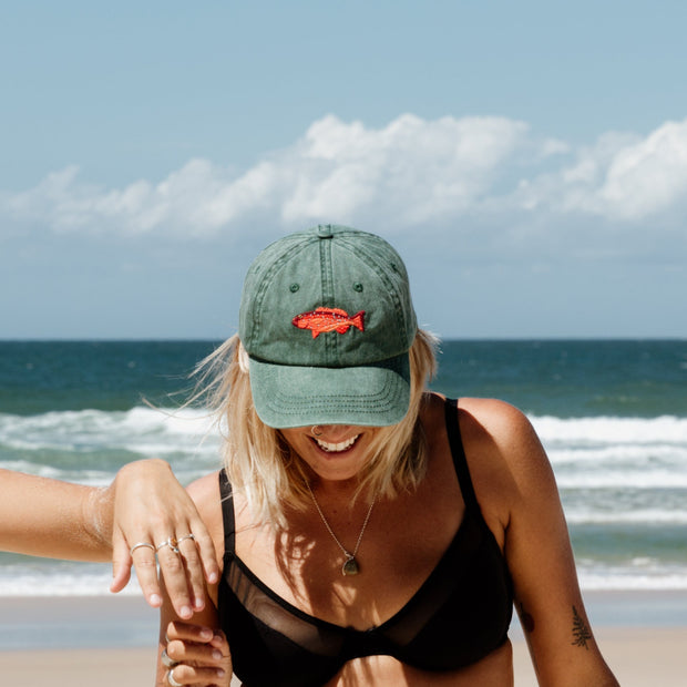 Faded green baseball cap with embroidered coral trout