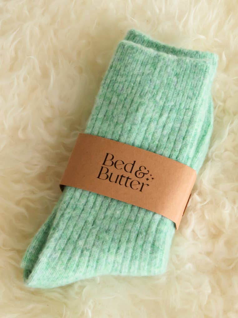 Soft mint green knee high socks worn while relaxing with a warm drink