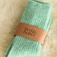 Soft mint green knee high socks worn while relaxing with a warm drink