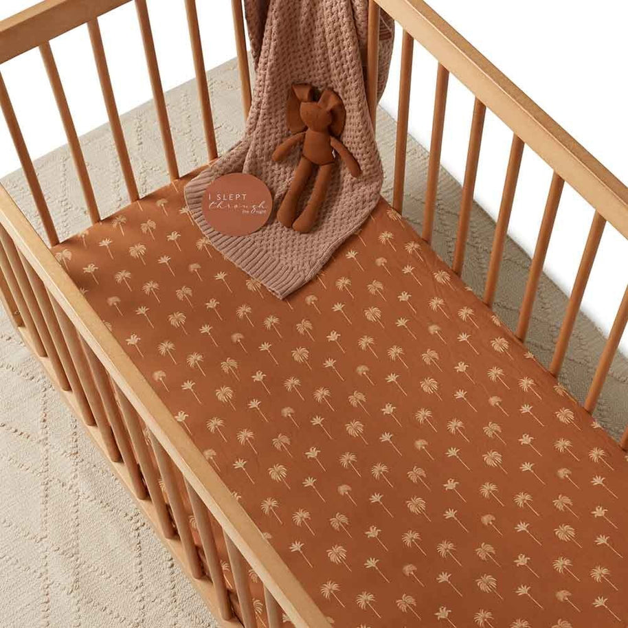Snuggle Hunny Bronze Palm Organic Fitted Cot Sheet in wooden cot