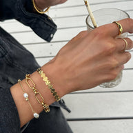 Gold pearl bracelet layered with other gold bracelets