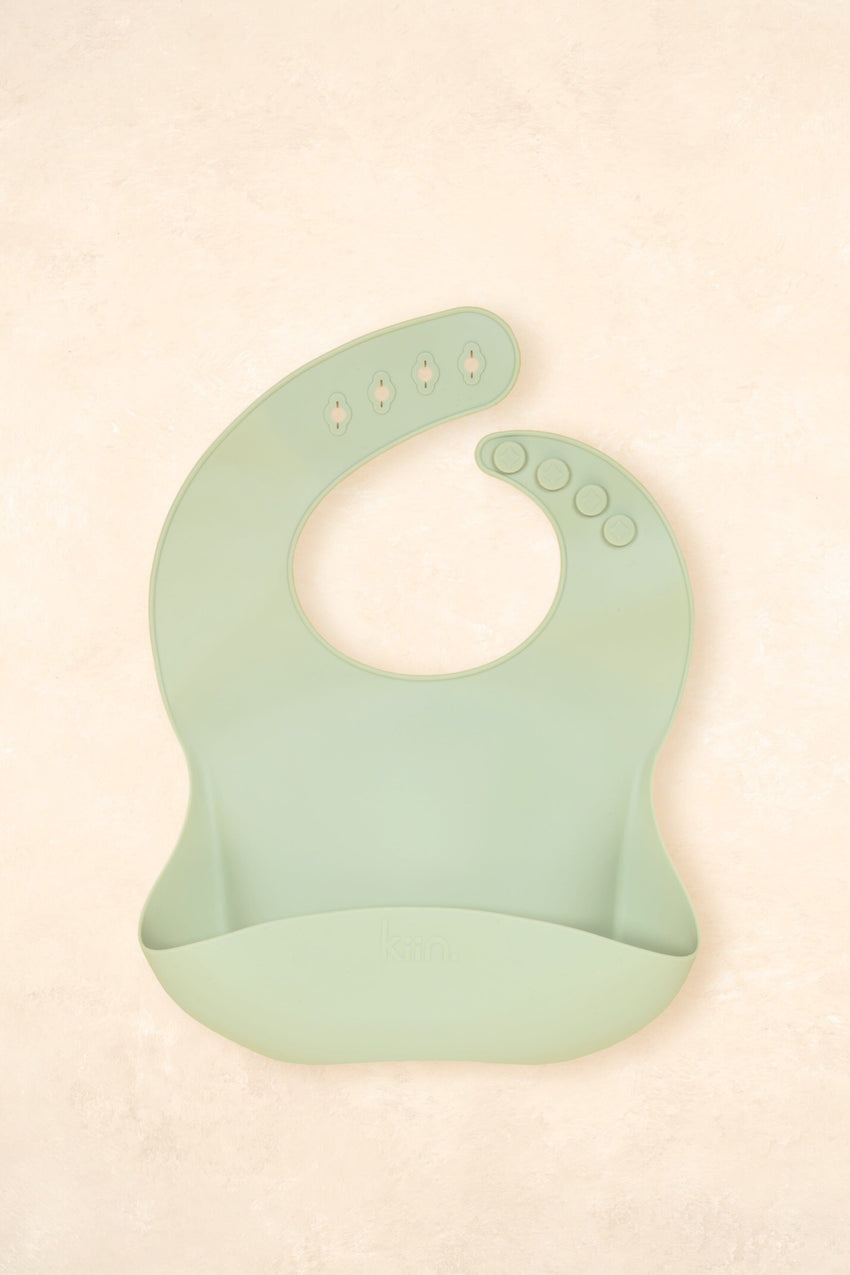 Kiin Baby Silicone Bib in Blossom – pink silicone feeding bib with adjustable neck and deep catch pocket.