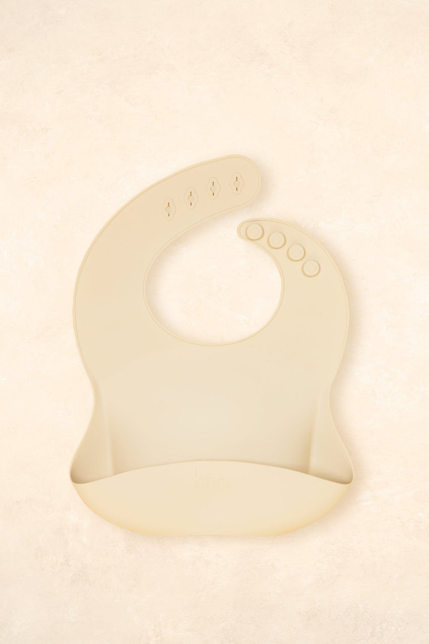 Kiin Baby Silicone Bib in Vanilla – soft food-grade silicone bib with adjustable neck and deep catch pocket.