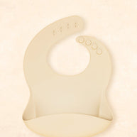 Kiin Baby Silicone Bib in Vanilla – soft food-grade silicone bib with adjustable neck and deep catch pocket.