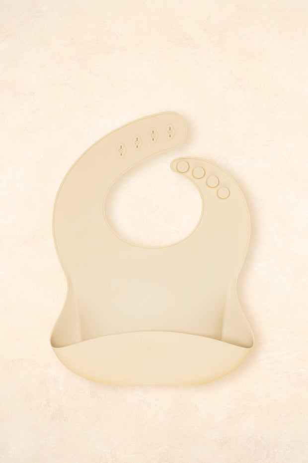 Kiin Baby Silicone Bib in Vanilla – soft food-grade silicone bib with adjustable neck and deep catch pocket.
