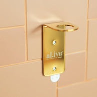 al.ive body Single Soap Bottle Holder – Gold. Wall-mounted stainless steel holder for one al.ive body bottle. Stylish gold finish, space-saving design.
